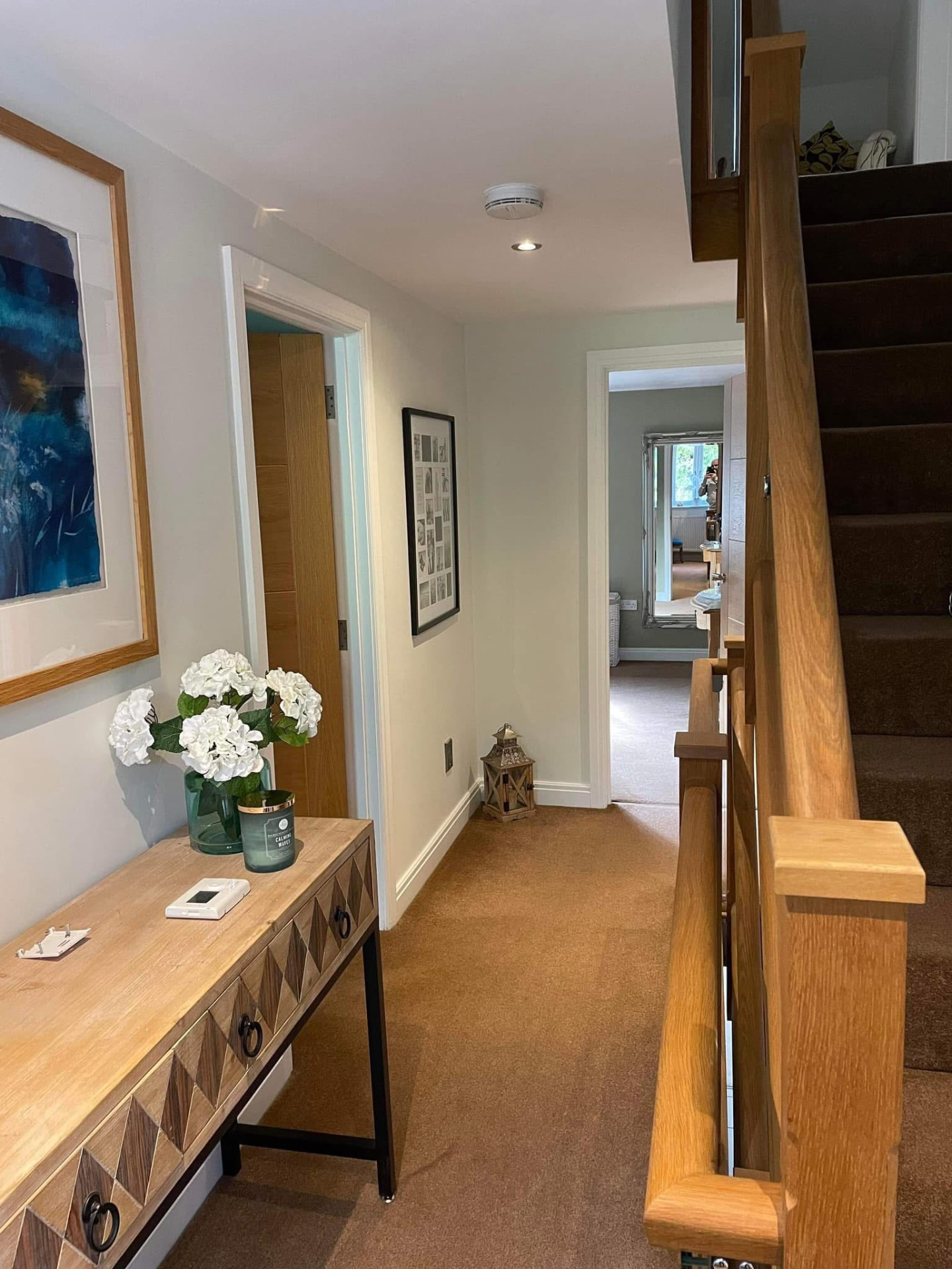 Finished hallway and landing with off-white walls, console table and blue artwork
