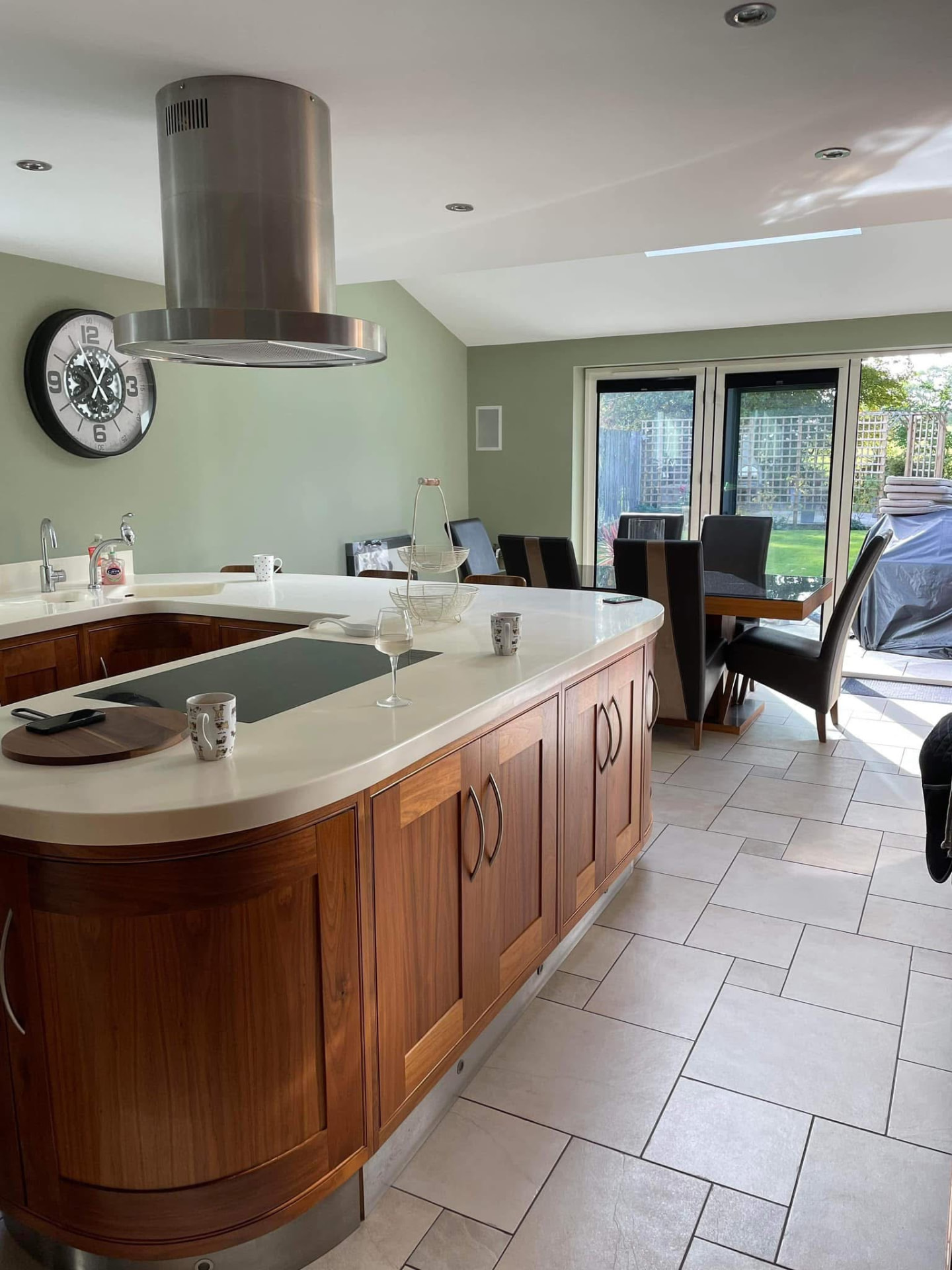 Finished kitchen with sage-green walls, curved island and a black-and-white wall clock