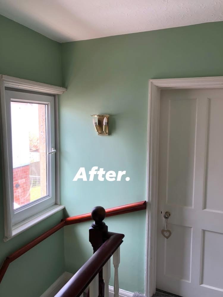 Landing finished in sage green with white door and window trim and a brass sconce