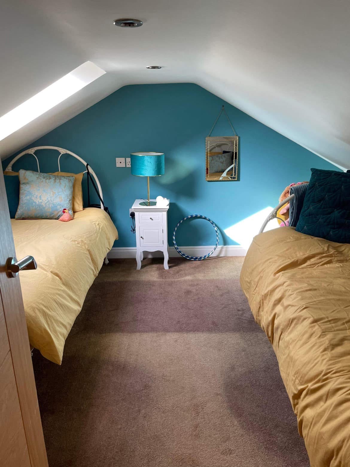 Attic bedroom with a teal feature wall, sloped ceiling and mustard bedding