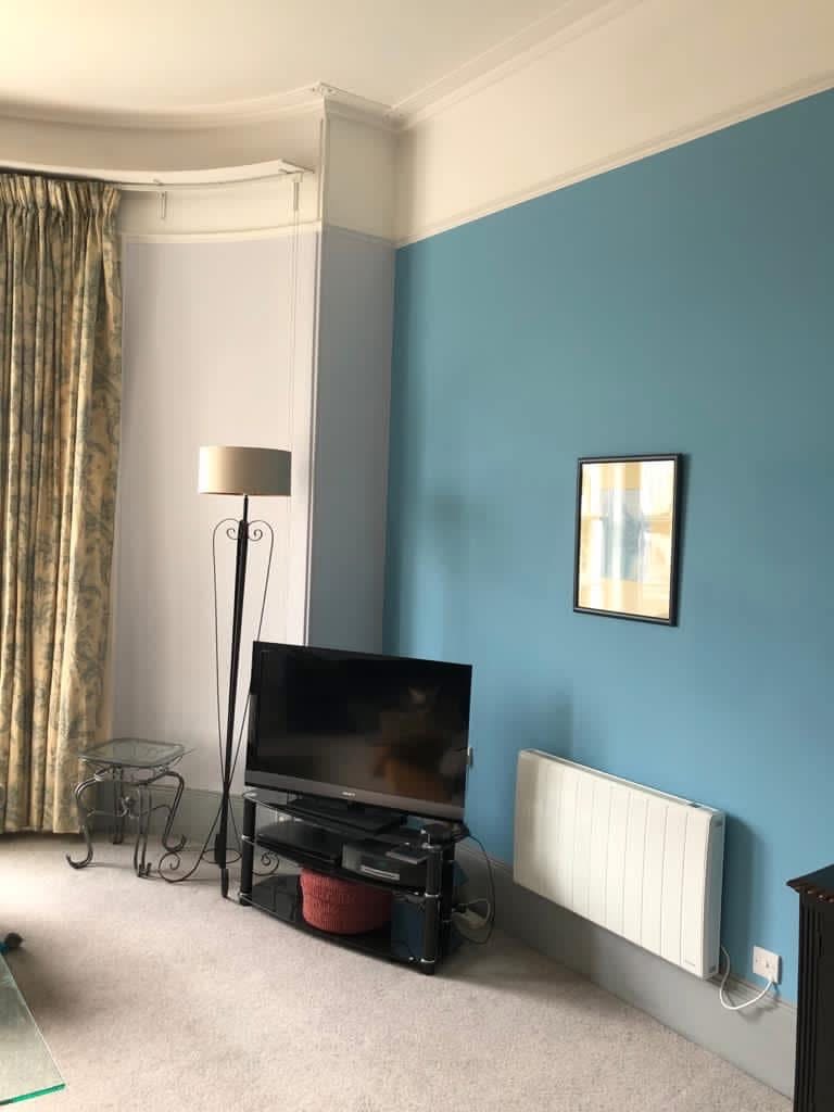 Living room with a bold teal feature wall meeting lavender-grey at a crisp corner line