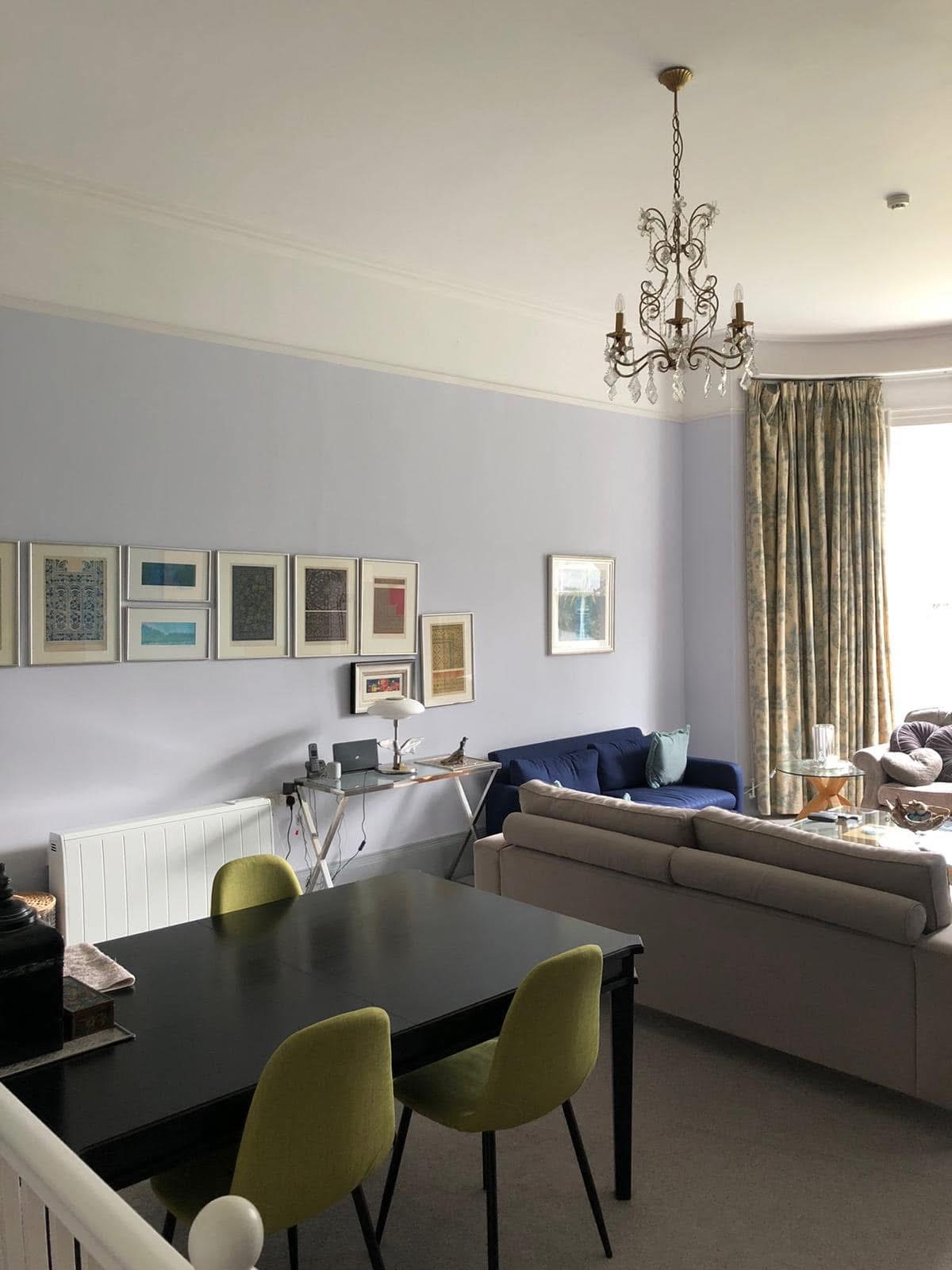 High-ceilinged room with a gallery wall of framed art, lavender-grey walls and a chandelier