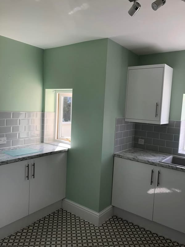 Finished kitchen corner with light green walls, grey subway tiles and marble-effect worktop