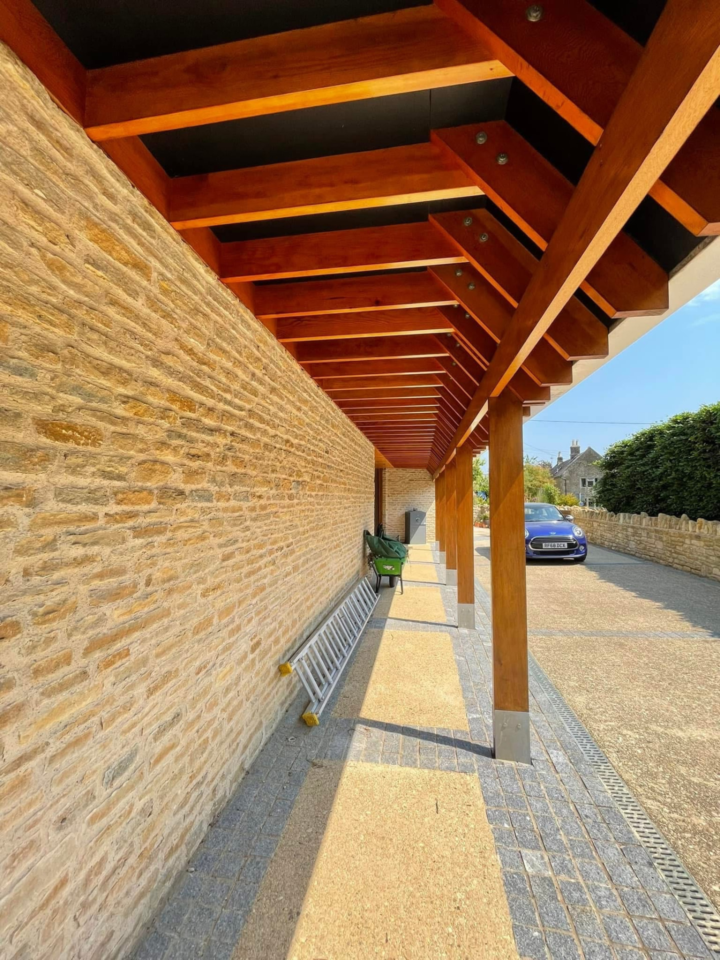 Covered walkway with freshly stained timber rafters and pillars over paving