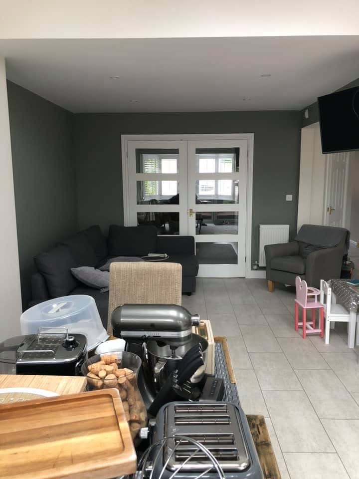 Wide view of a finished living and dining room with a sage-green feature wall