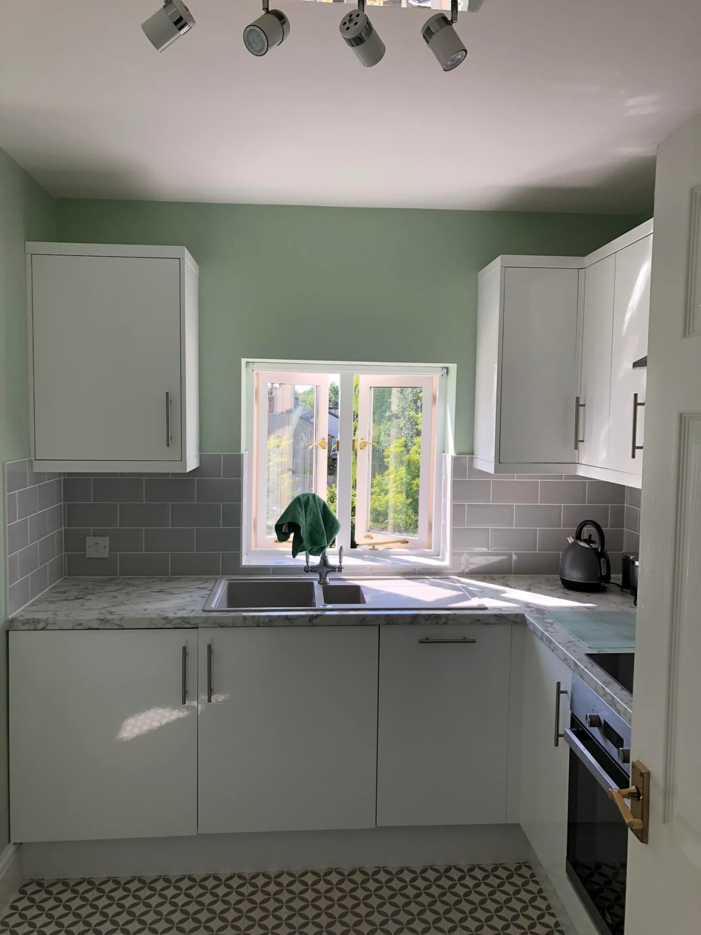 Finished kitchen with light green walls, white cabinetry and a four-bulb spotlight