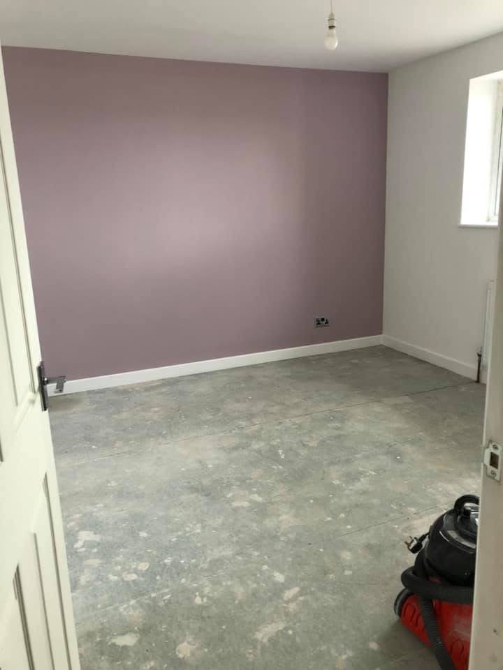 Room with a muted mauve feature wall and crisp white skirting and trim