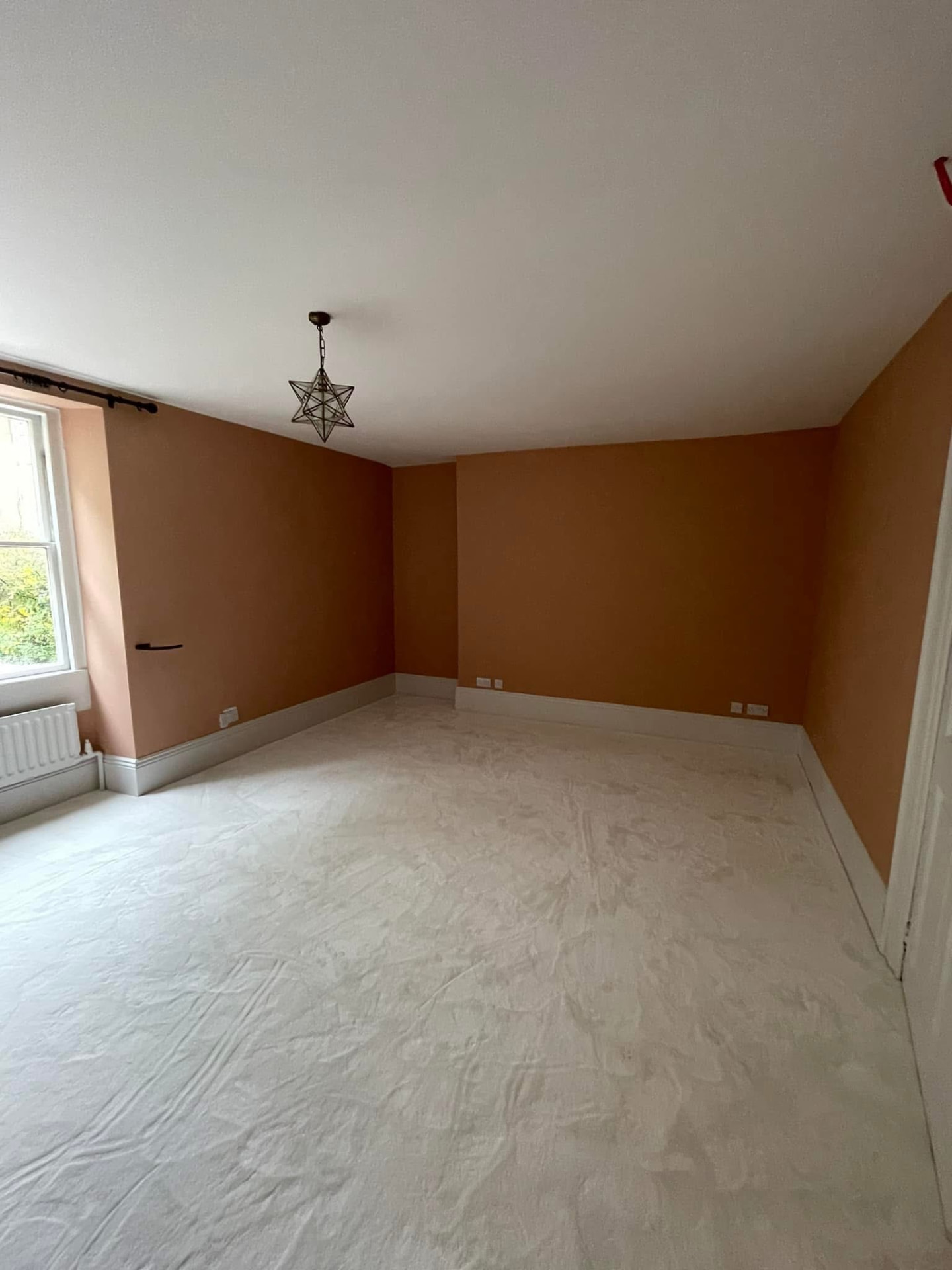 Bedroom with a terracotta feature wall, star pendant light and light carpet